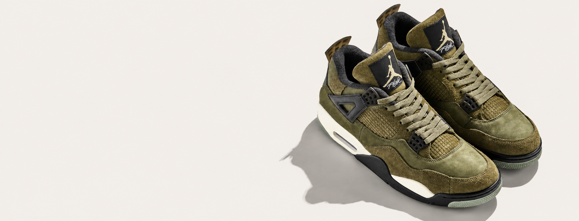 A pair of Air Jordan 4 Retro Low 'Olive Green' sneakers shown from a three-quarters angle on a light beige background with a soft shadow.